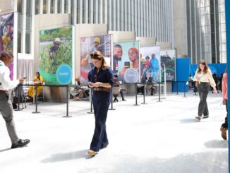 Besucher der Frühjahrstagung des Internationalen Währungsfonds (IWF) in Washington schlendern durch ein helles Foyer, in dem Stellwände mit Porträts stehen.