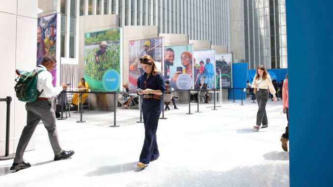 Besucher der Frühjahrstagung des Internationalen Währungsfonds (IWF) in Washington schlendern durch ein helles Foyer, in dem Stellwände mit Porträts stehen.